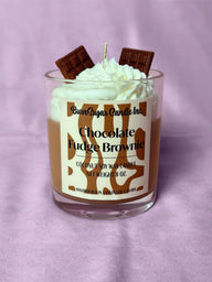 Candle with whipped cream and chocolate pieces on a purple background