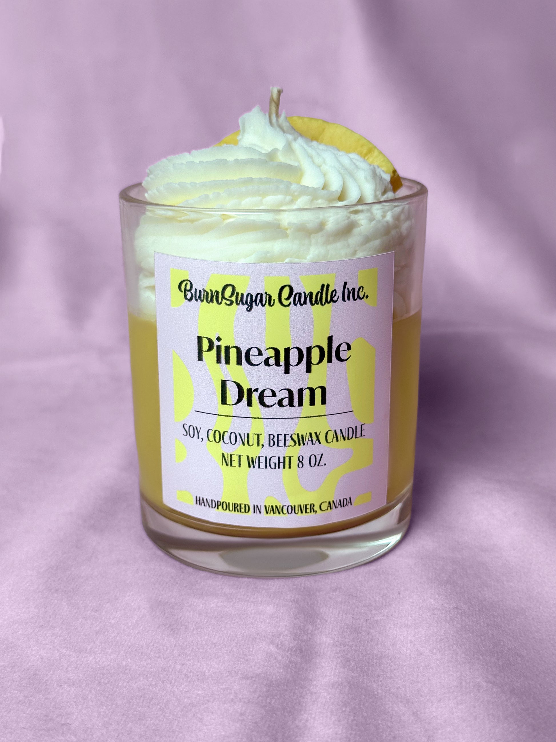 Candle labeled 'Pineapple Dream' with a pineapple slice on a purple background