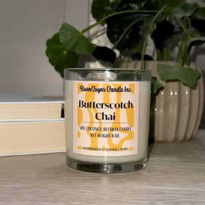 Butterscotch Chai candle with a plant and books in the background