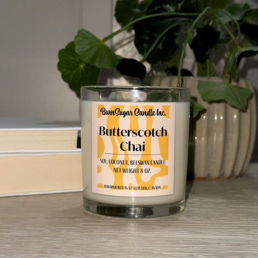 Butterscotch Chai candle with a plant and books in the background