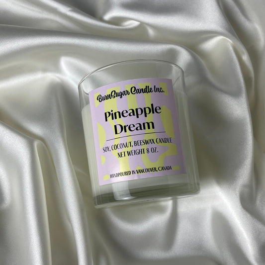 Candle labeled 'Pineapple Dream' on a satin surface